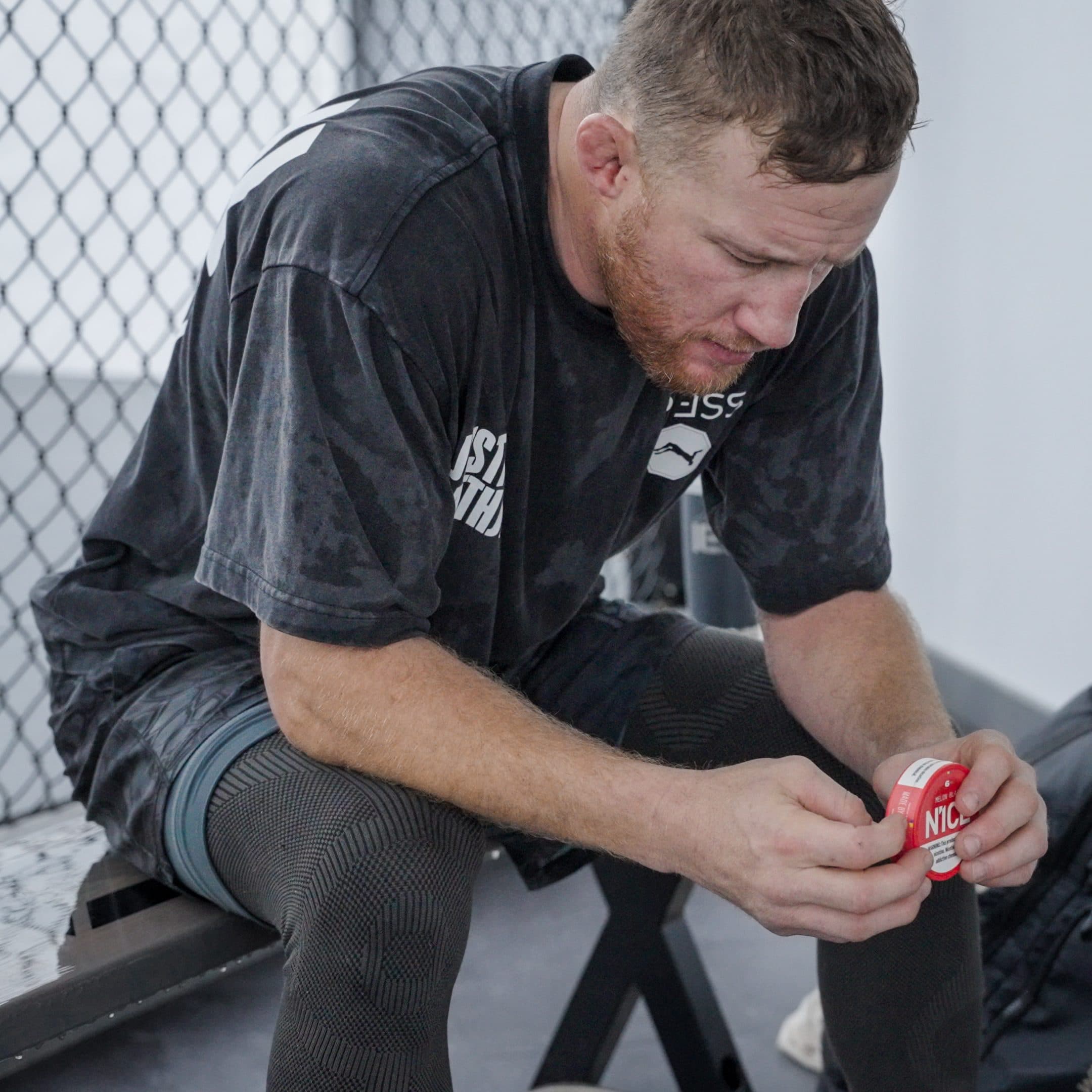 Gaethje seated on a bench opening a tin of N1CE